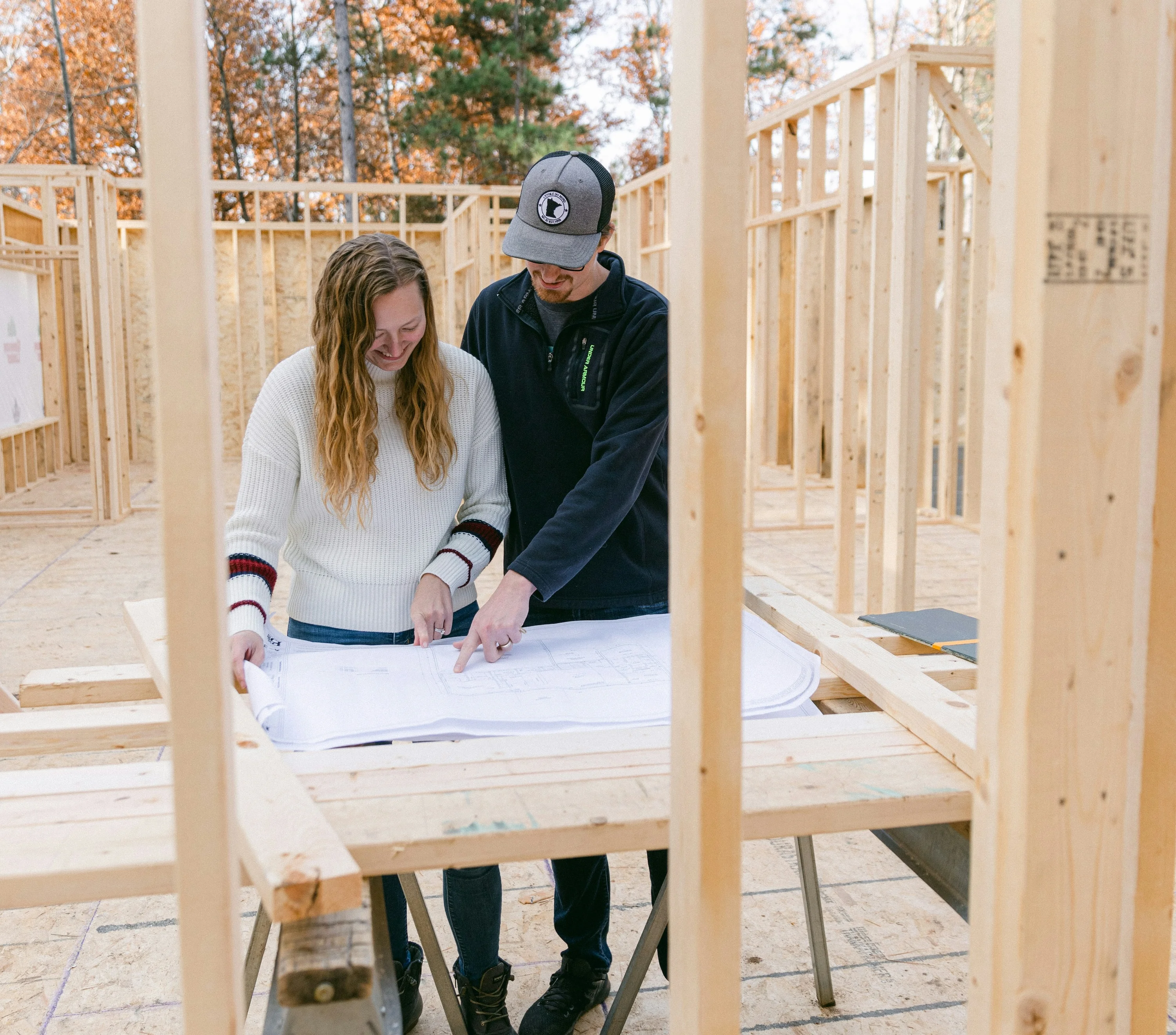 Dossier de déclaration de sinistre posé sur une table, avec photos et devis Deux propriétaires travaillant sur les plans de leur maison